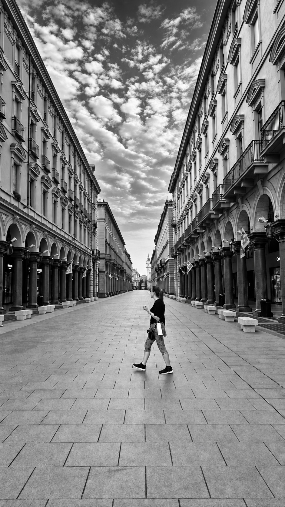 Une silhouette traverse la perspective des arcades.
